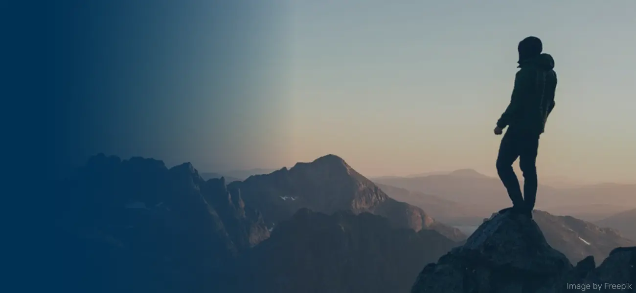 Person steht auf einem Berg und schaut in die Weite